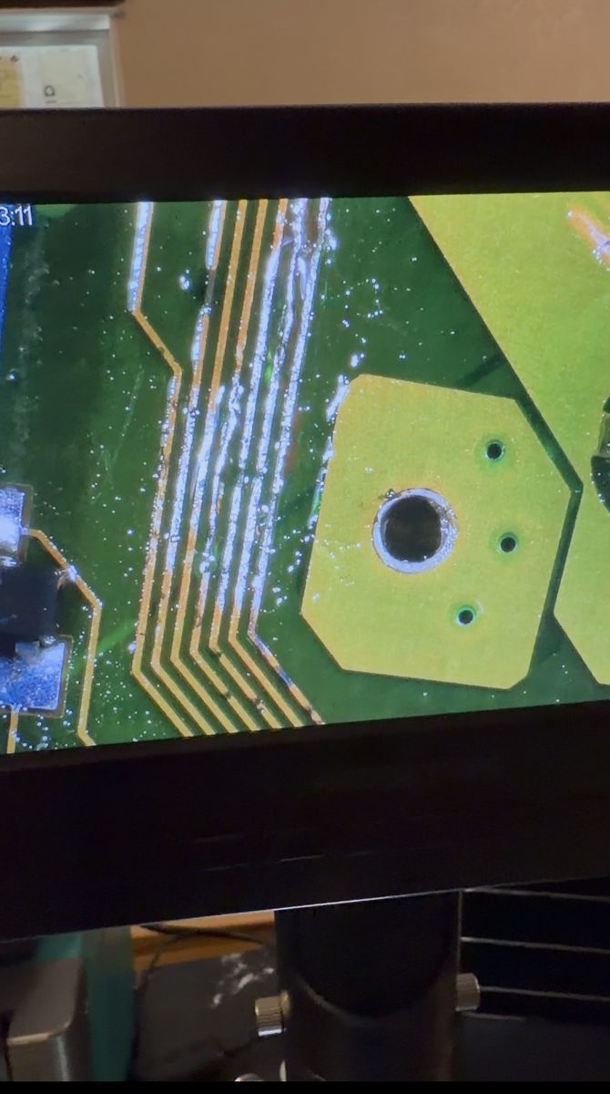 Technician microscope view of ECU circuit-board traces during repair inspection